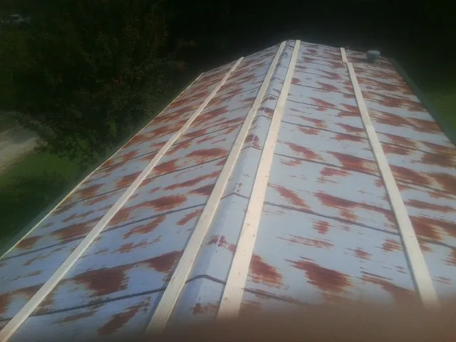 Rusted metal roof panels with new wood purlins before replacement — Storm Damage Roof Repair in Blue Mounds by Roofing Brothers