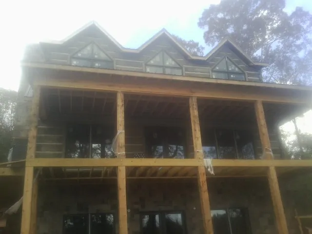 Dormers and porch framing on a large log home under construction — Roof Coating work by our crew in Blue Mounds