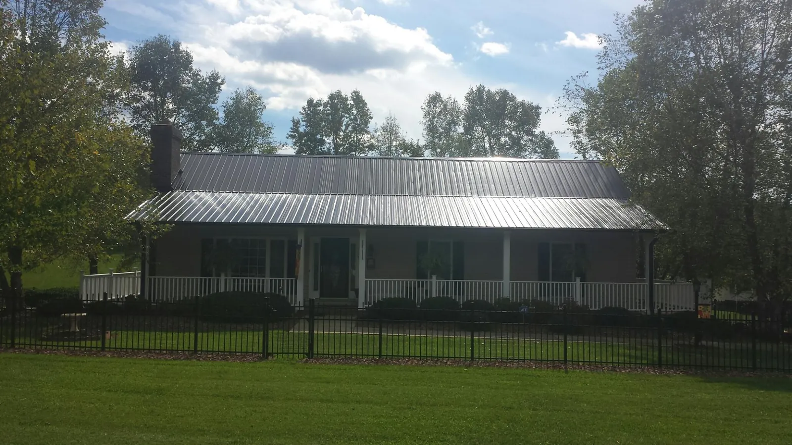 Gray metal roof on a brick ranch with a full width front porch — Gutter Guard Installation work by our crew in Blue Mounds