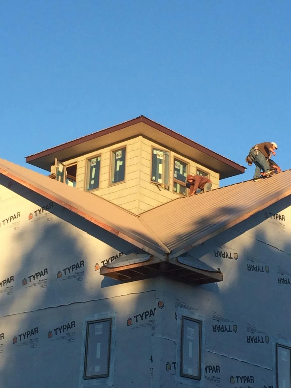 Roofers working around a rooftop cupola on a new metal roof at sunset — Roof Waterproofing in Blue Mounds by Roofing Brothers